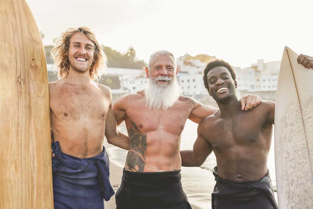 hommes-surfeurs multiraciaux-à-la-plage-avec-surfboard